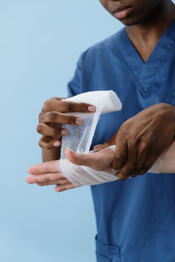 A healthcare professional wrapping a patients hand with gauze for injury care.